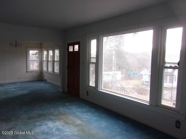 empty room featuring plenty of natural light and dark colored carpet