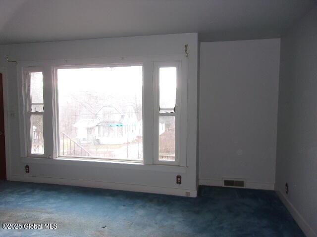 empty room with dark colored carpet and plenty of natural light