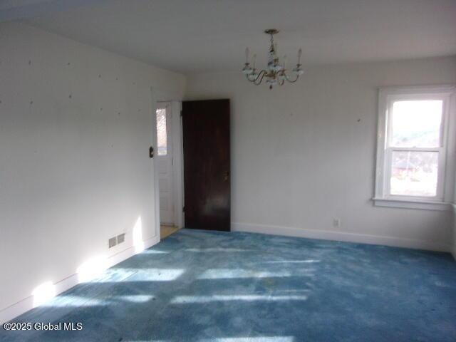 unfurnished room featuring dark carpet and an inviting chandelier