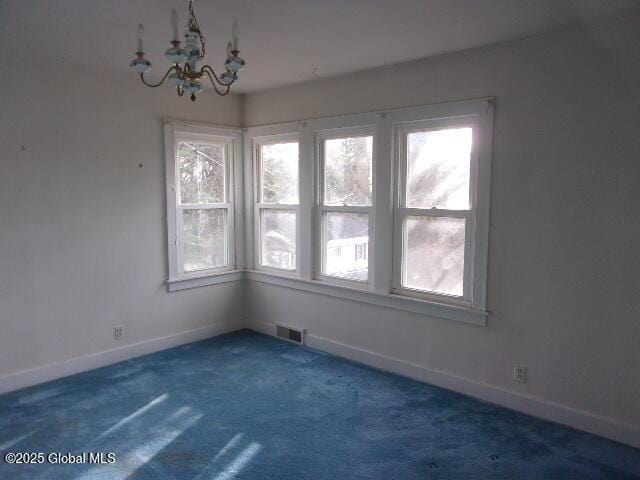 unfurnished room featuring dark carpet and a chandelier