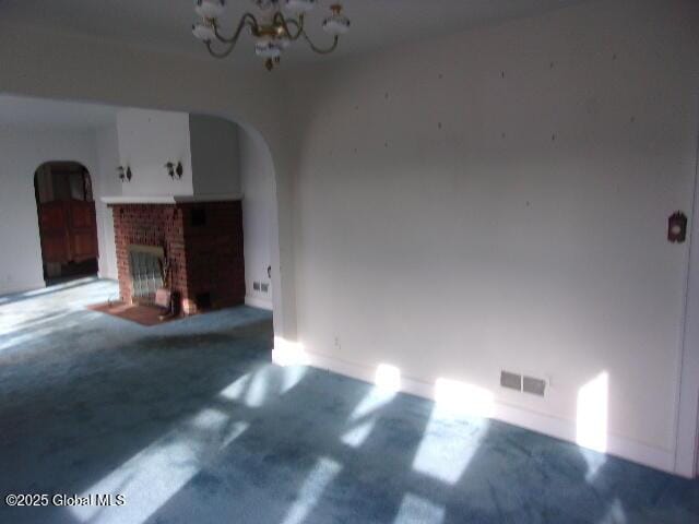 unfurnished living room featuring a fireplace and an inviting chandelier