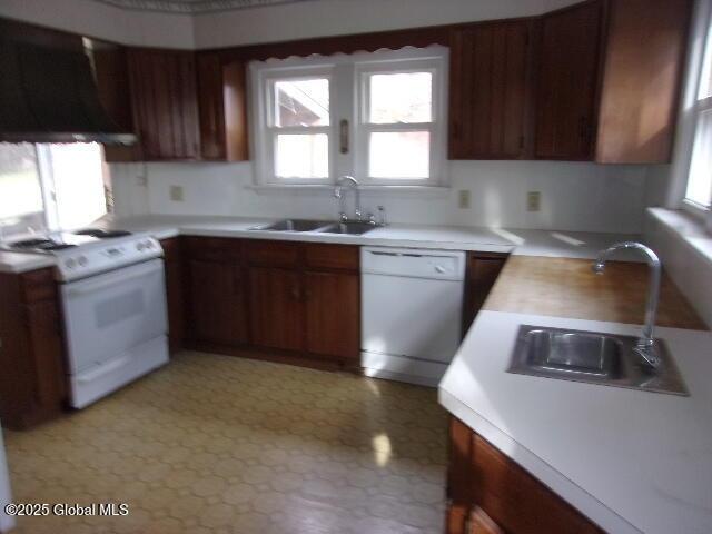 kitchen with white appliances, wall chimney exhaust hood, and sink