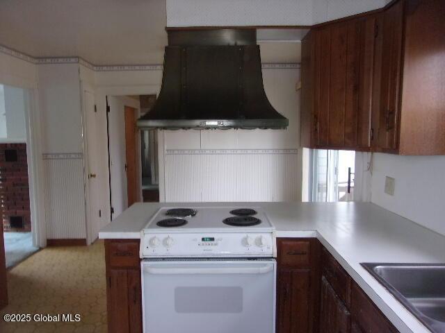 kitchen featuring sink, white electric range oven, extractor fan, and kitchen peninsula