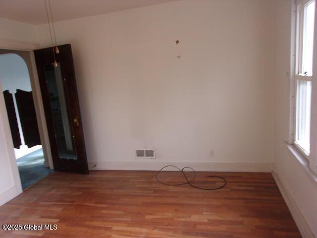 empty room with a healthy amount of sunlight and hardwood / wood-style floors