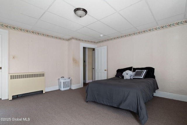 bedroom with a drop ceiling, radiator heating unit, and carpet flooring