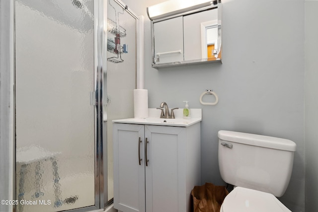 bathroom with a shower with shower door, toilet, and vanity