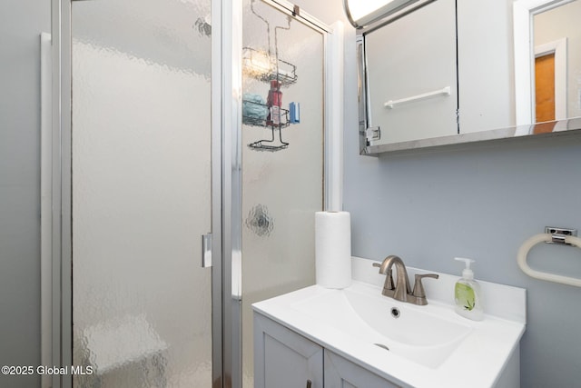 bathroom featuring a shower with door and vanity