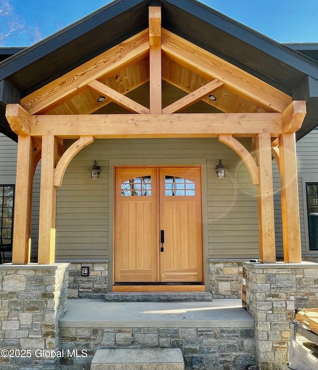 doorway to property with covered porch and stone siding