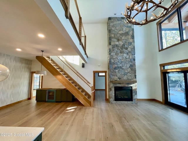 unfurnished living room with light wood-style floors, wine cooler, plenty of natural light, and stairway