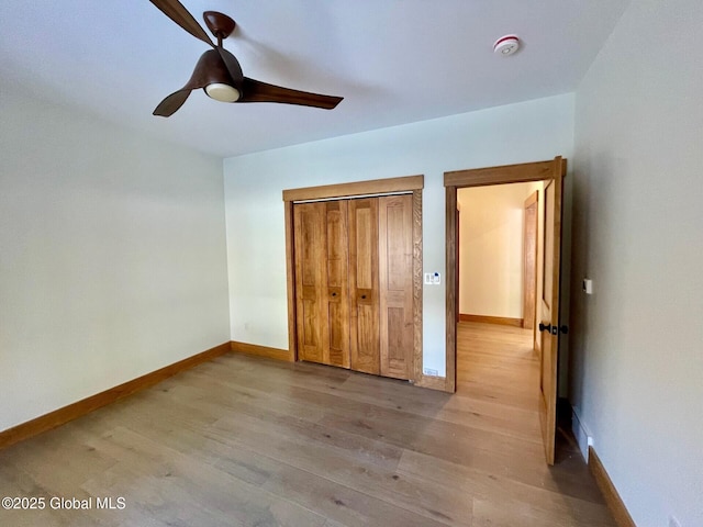 unfurnished bedroom featuring light wood-style floors, a ceiling fan, baseboards, and a closet