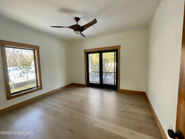 empty room featuring light wood-style floors, visible vents, ceiling fan, and baseboards