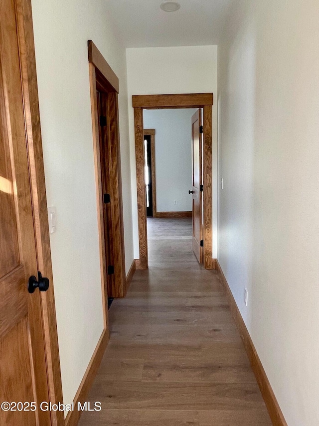 corridor featuring light wood-type flooring and baseboards