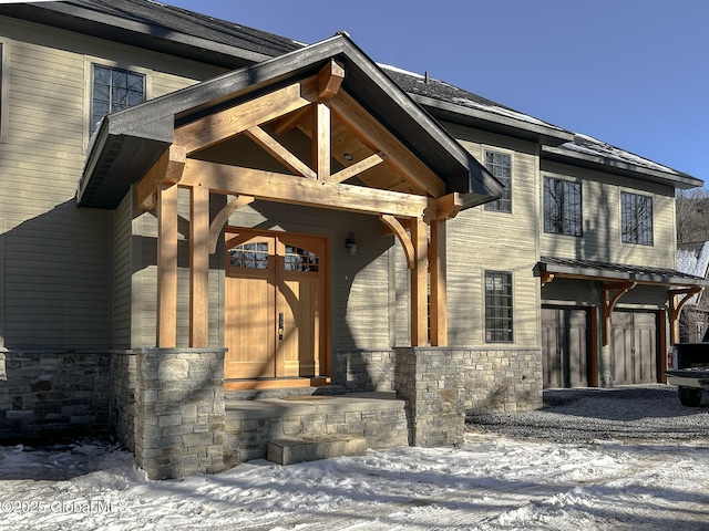 snow covered property entrance featuring stone siding