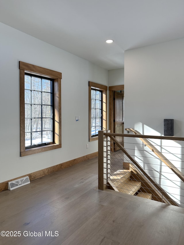 interior space with recessed lighting, wood finished floors, visible vents, an upstairs landing, and baseboards