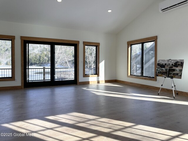 empty room with vaulted ceiling, an AC wall unit, wood finished floors, and baseboards