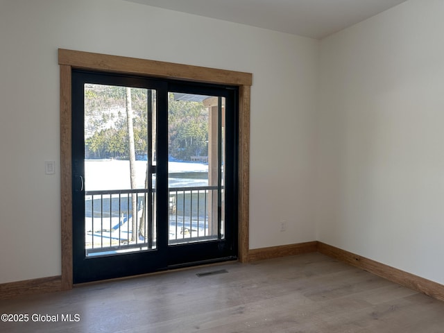 empty room featuring a water view, light wood finished floors, plenty of natural light, and visible vents