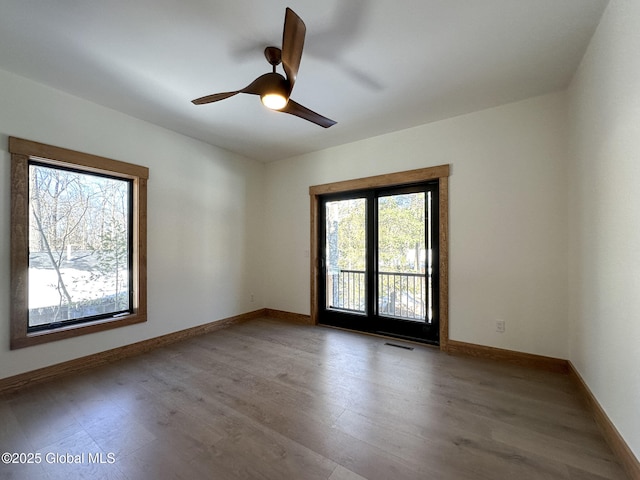 unfurnished room with light wood finished floors, a ceiling fan, visible vents, and baseboards