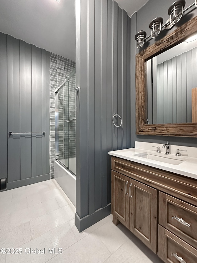 bathroom featuring shower / bath combination with glass door, wood walls, and vanity