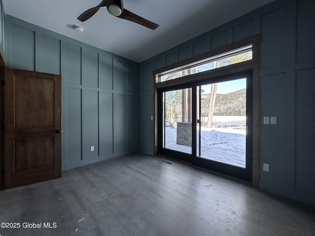 spare room with a ceiling fan, a decorative wall, and wood finished floors