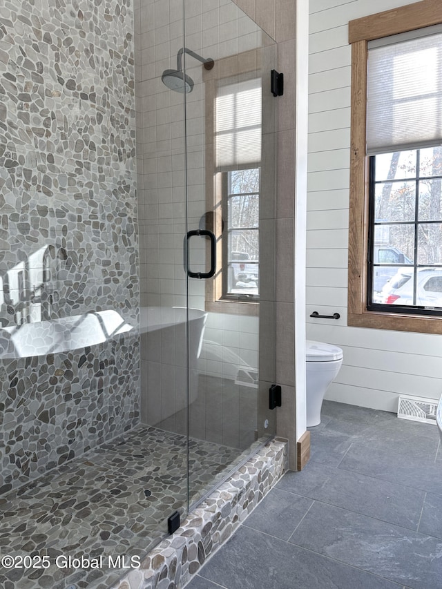 full bathroom featuring toilet, a stall shower, visible vents, and wood walls