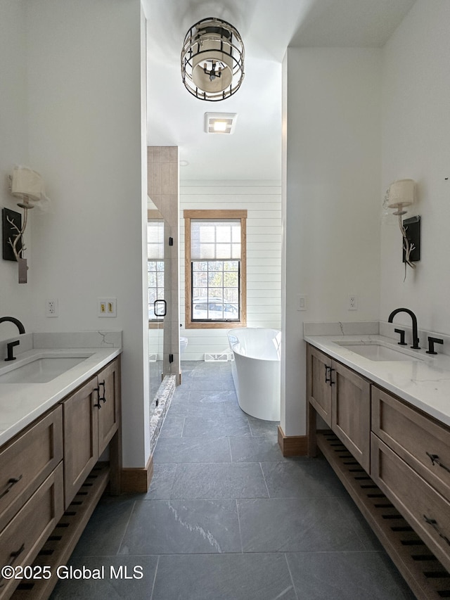 full bath featuring two vanities, a soaking tub, a sink, and a shower stall