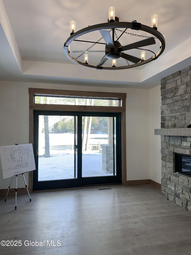 unfurnished living room featuring a fireplace, a raised ceiling, and a wealth of natural light