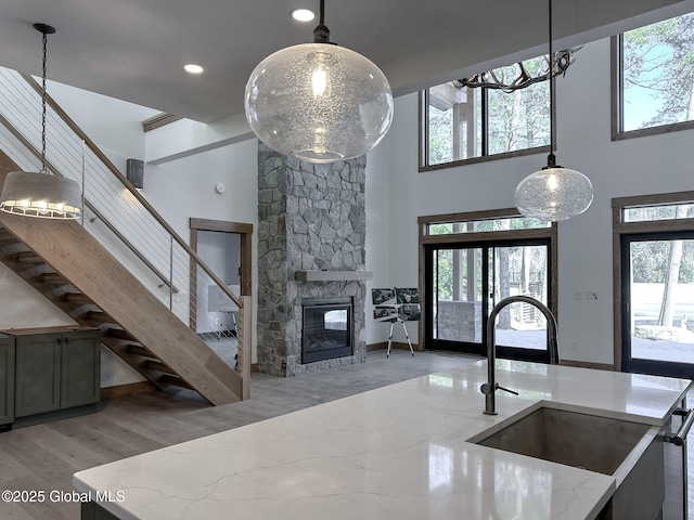 kitchen with hanging light fixtures, plenty of natural light, a sink, and light stone countertops