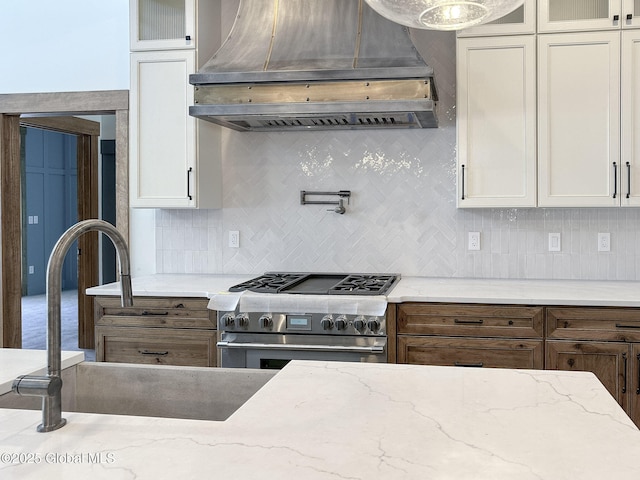 kitchen with stainless steel stove, white cabinets, decorative backsplash, glass insert cabinets, and custom range hood