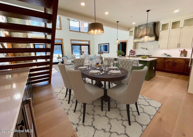 dining room with a high ceiling, light wood-type flooring, and recessed lighting