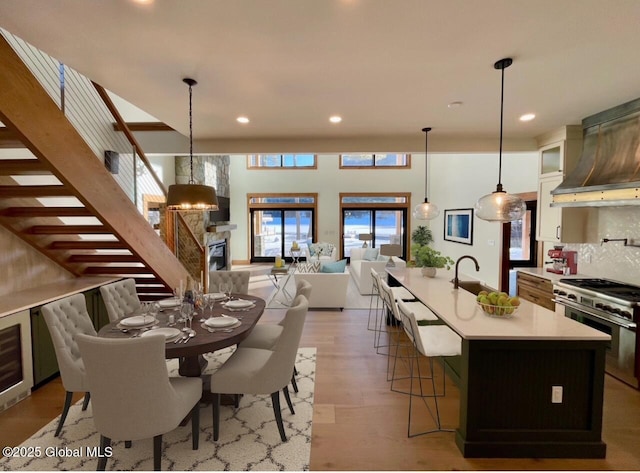 kitchen with light countertops, high end stainless steel range oven, a center island with sink, glass insert cabinets, and pendant lighting