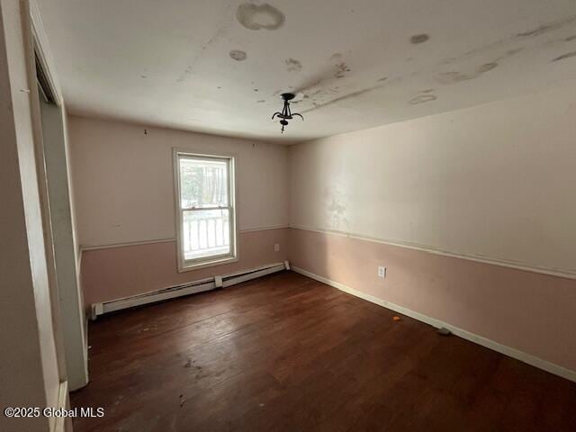 unfurnished room featuring baseboard heating and dark wood-type flooring