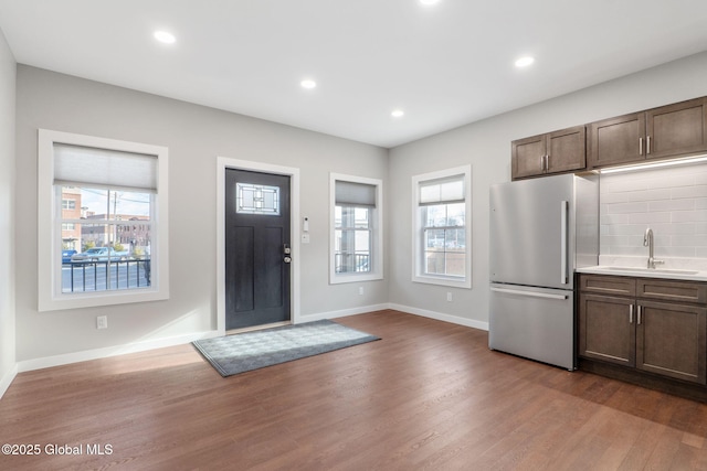 kitchen featuring dark wood-type flooring, decorative backsplash, sink, stainless steel fridge, and dark brown cabinets