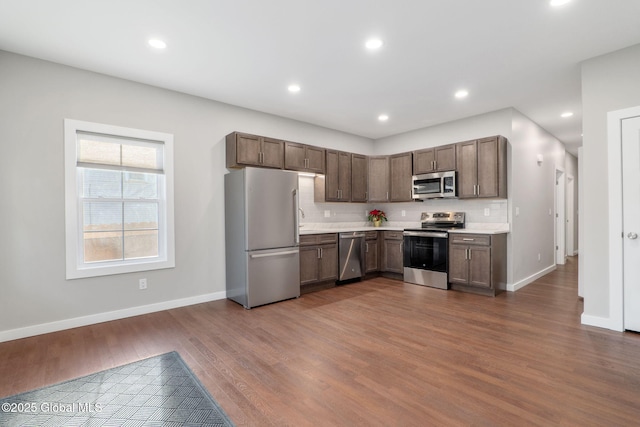 kitchen with sink, hardwood / wood-style floors, appliances with stainless steel finishes, and tasteful backsplash