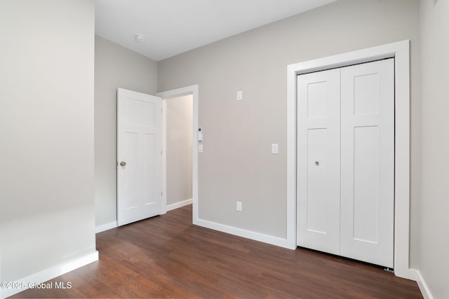 unfurnished bedroom with a closet and dark hardwood / wood-style flooring