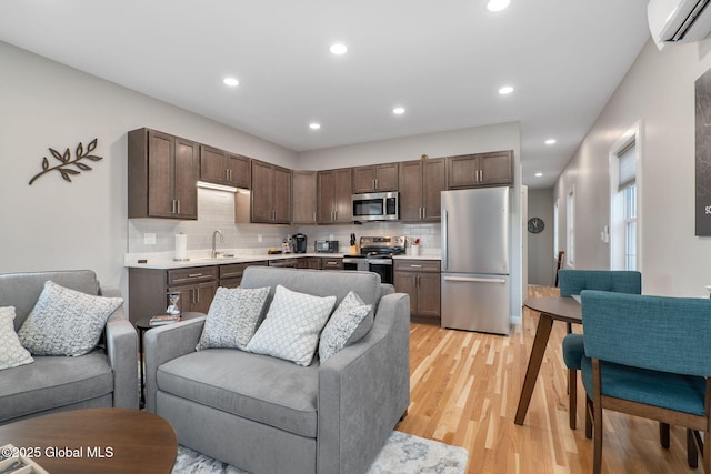 living room with a wall unit AC, light hardwood / wood-style flooring, and sink