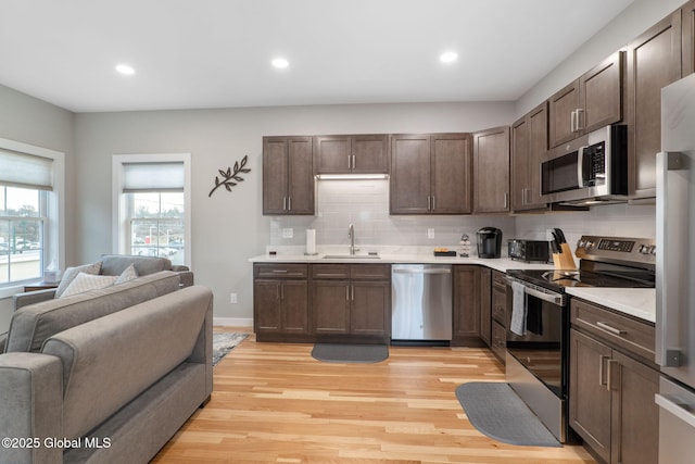 kitchen with light wood-type flooring, appliances with stainless steel finishes, sink, and dark brown cabinets