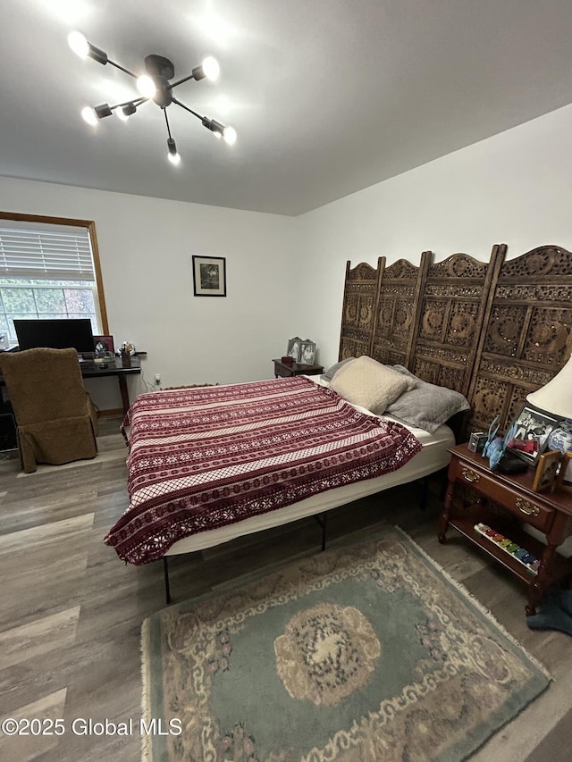 bedroom with wood-type flooring and ceiling fan with notable chandelier