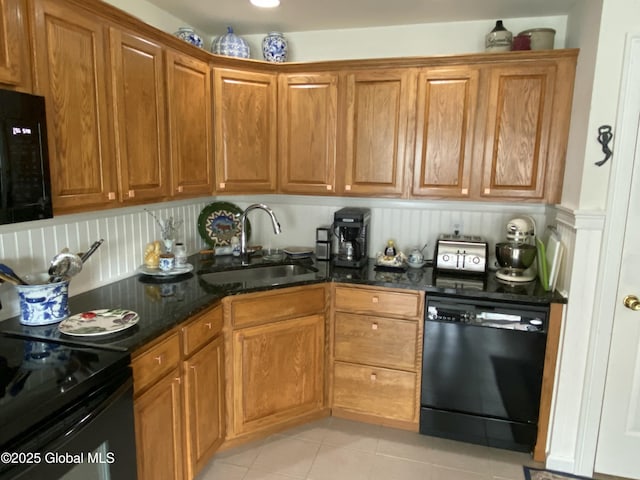 kitchen with sink, light tile patterned floors, black appliances, and dark stone counters