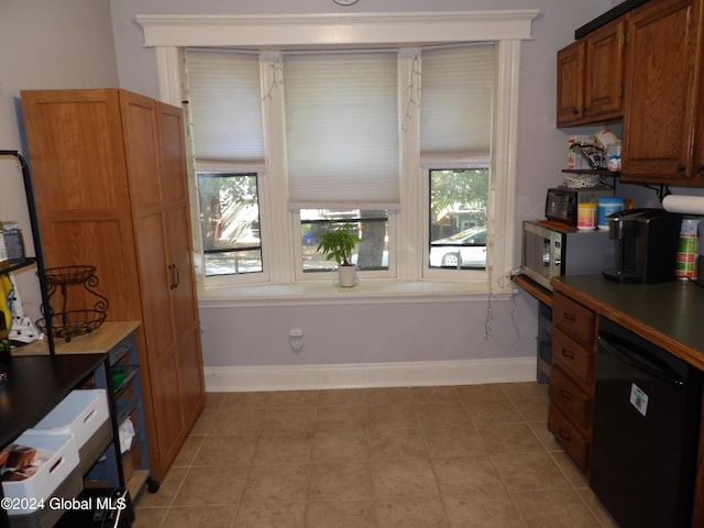 kitchen featuring a healthy amount of sunlight, light tile patterned flooring, and black dishwasher