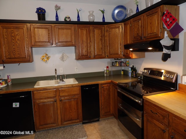 kitchen with light tile patterned floors, sink, range with two ovens, and black dishwasher