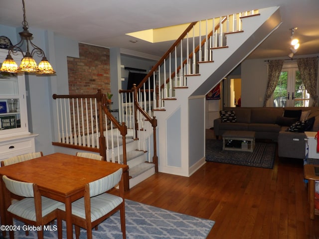 dining room with dark wood-type flooring, a notable chandelier, crown molding, and french doors