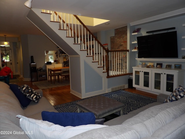 living room with built in features, crown molding, and hardwood / wood-style flooring