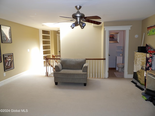 living area with ceiling fan, built in features, and light carpet