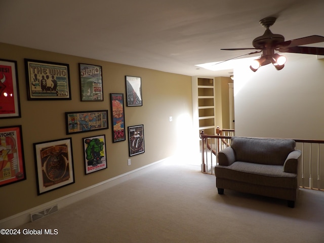 living area featuring ceiling fan, light colored carpet, and built in shelves