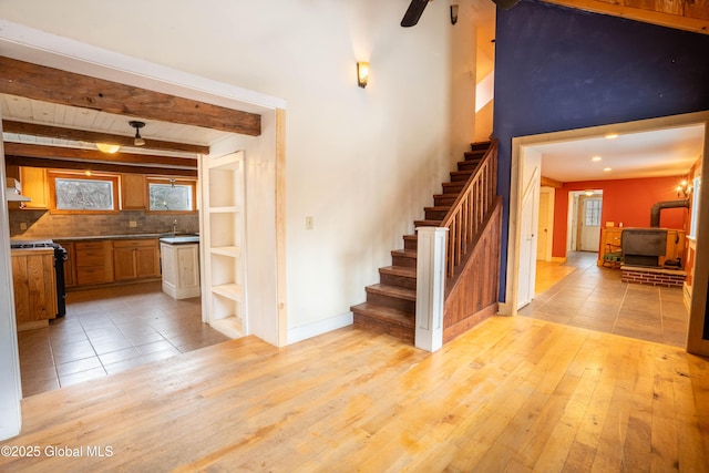 staircase featuring hardwood / wood-style flooring, a wood stove, sink, and beamed ceiling