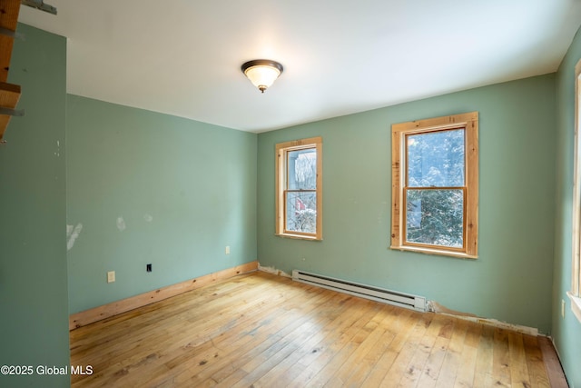 empty room with a baseboard heating unit and light hardwood / wood-style flooring