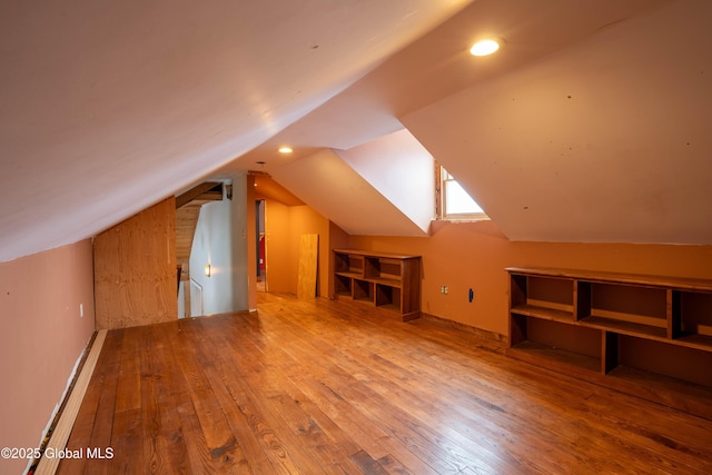 additional living space with wood-type flooring and vaulted ceiling