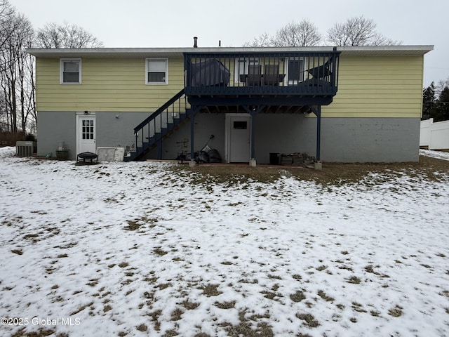 snow covered house featuring central AC and a deck