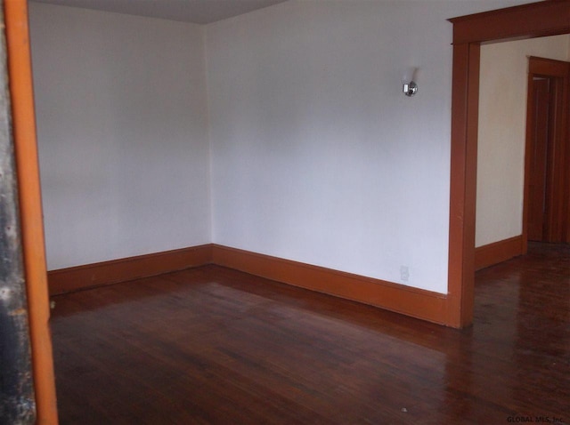 unfurnished room featuring dark wood-style floors and baseboards