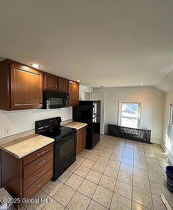 kitchen featuring vaulted ceiling, light tile patterned floors, and black appliances